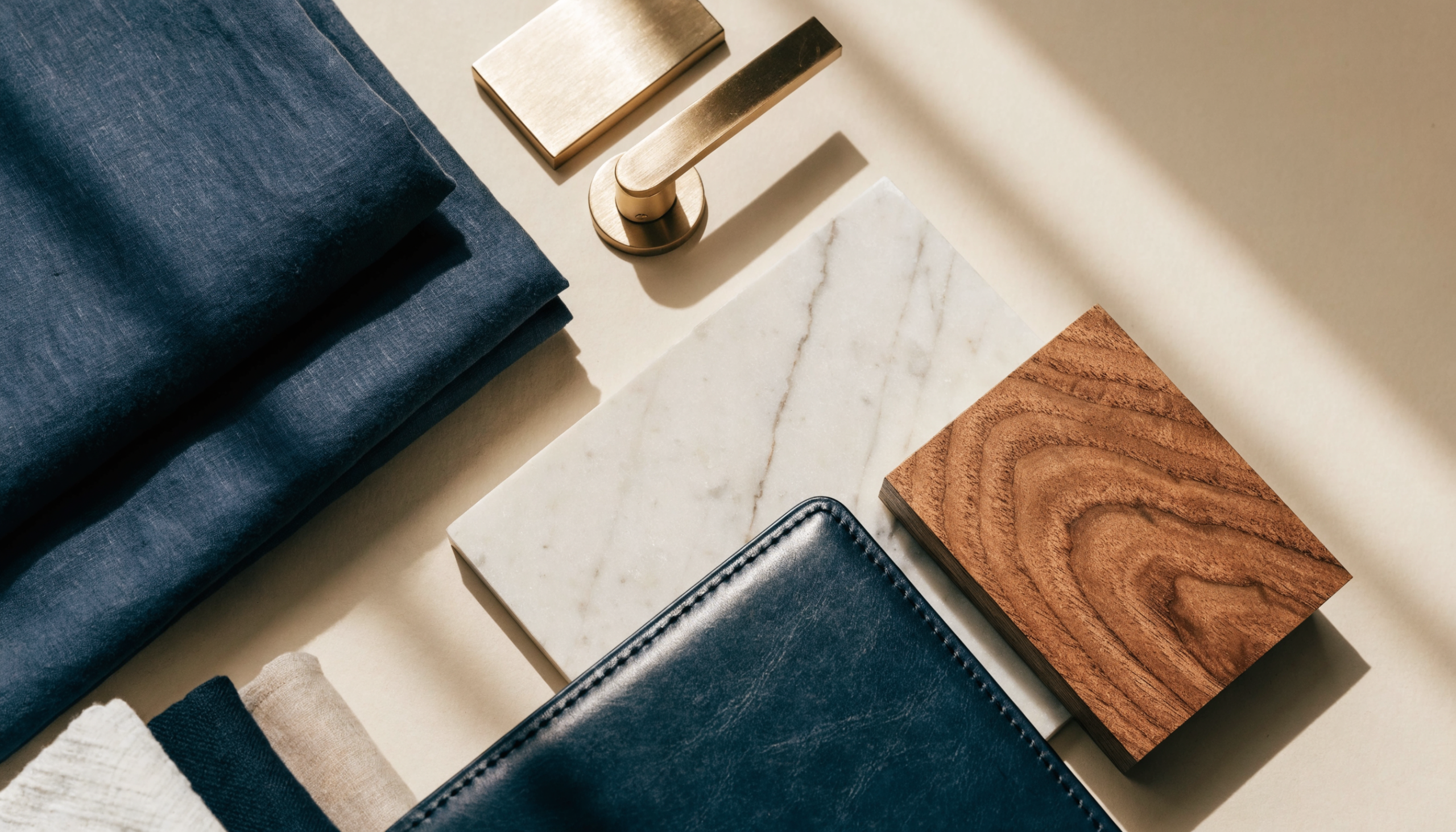 Hotel interior specification materials: folded linens, brushed gold hardware, marble and timber swatches and a specification binder, illustrating hotel procurement terminology